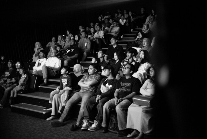 spectateurs assis dans une salle de cinéma en noir et blanc